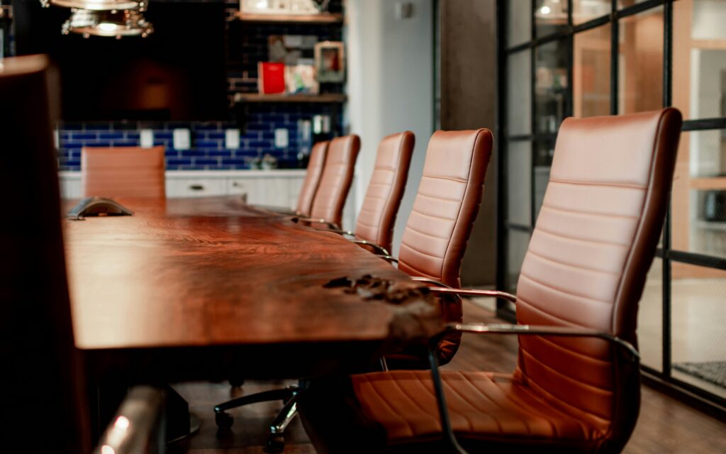 Empty conference room with large wooden table and leather chairs